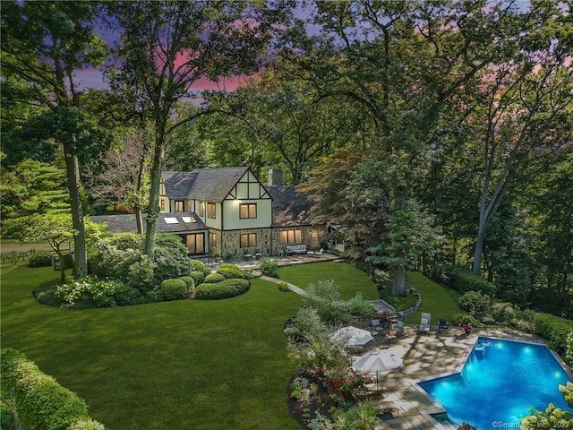 back house at dusk with a lawn and a patio