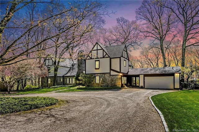 english style home featuring a yard and a garage