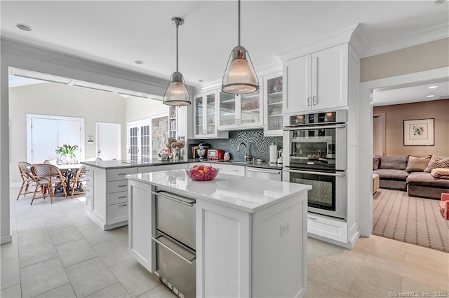 kitchen featuring appliances with stainless steel finishes, white cabinetry, tasteful backsplash, a kitchen island, and decorative light fixtures