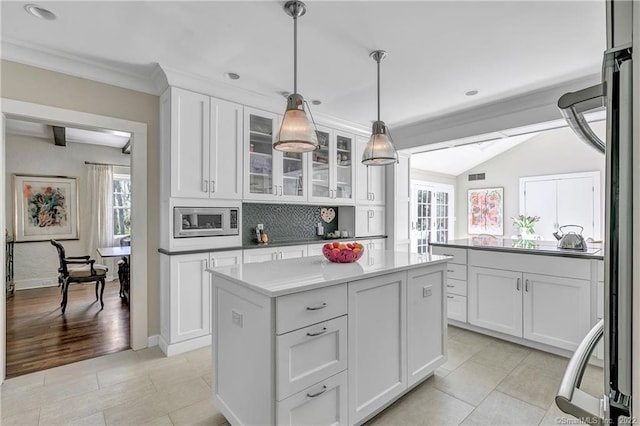 kitchen with pendant lighting, white cabinetry, stainless steel microwave, and a kitchen island