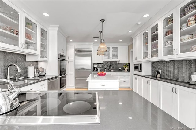 kitchen featuring hanging light fixtures, built in appliances, sink, and white cabinets