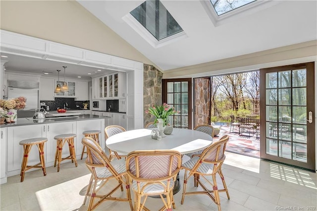 tiled dining space with lofted ceiling with skylight