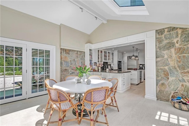 dining room featuring high vaulted ceiling, a skylight, beamed ceiling, and track lighting