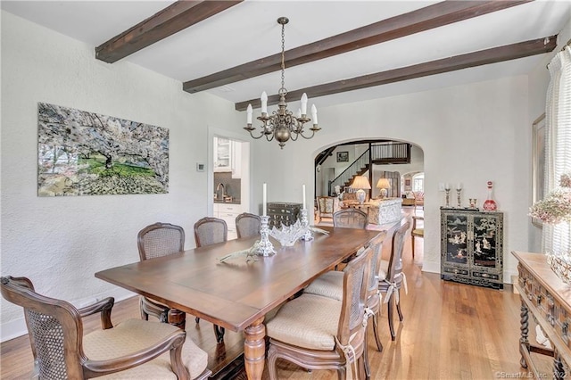 dining space with an inviting chandelier, beam ceiling, and light hardwood / wood-style floors