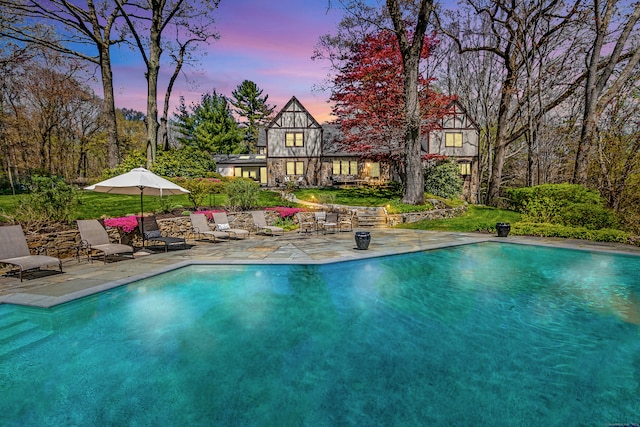 pool at dusk featuring a patio