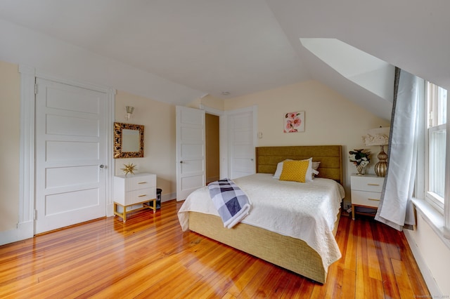 bedroom with hardwood / wood-style flooring, lofted ceiling, and multiple windows