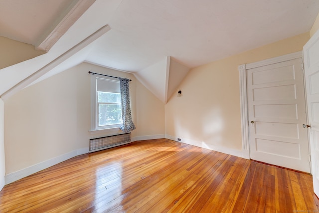 additional living space featuring radiator, light hardwood / wood-style flooring, and lofted ceiling