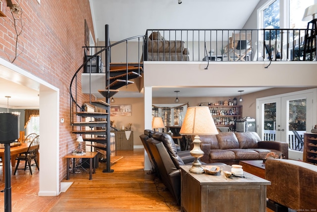 living room with wood-type flooring, a high ceiling, french doors, and brick wall