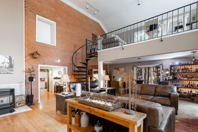 living room with brick wall, high vaulted ceiling, light hardwood / wood-style floors, and track lighting