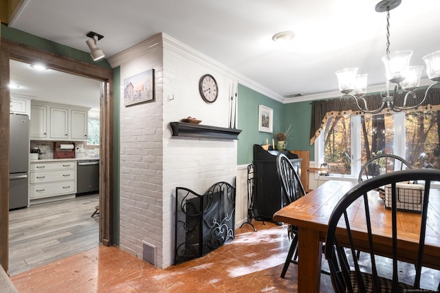 dining area featuring a brick fireplace, crown molding, and a notable chandelier