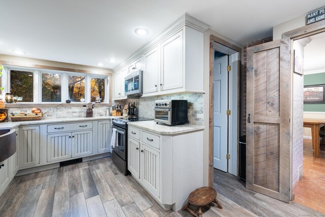 kitchen with tasteful backsplash, black / electric stove, white cabinets, and light wood-type flooring