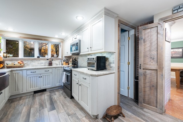 kitchen with white cabinets, electric stove, backsplash, and light hardwood / wood-style flooring