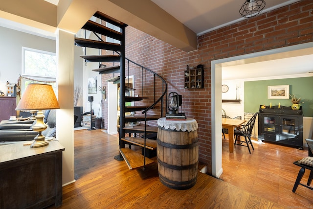 stairway with wood-type flooring, ornamental molding, and brick wall