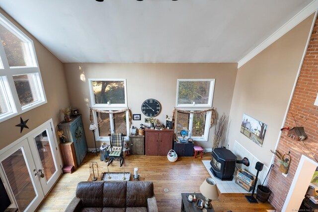 living room with a wood stove, light hardwood / wood-style flooring, french doors, and ornamental molding