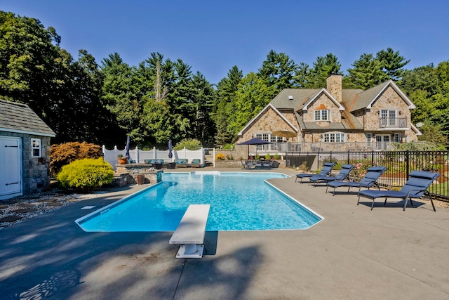 view of swimming pool featuring a patio area and a diving board