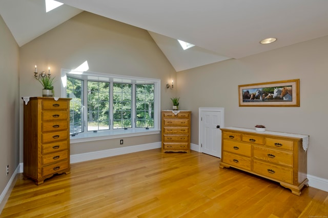 sitting room featuring light wood-type flooring, a skylight, and high vaulted ceiling