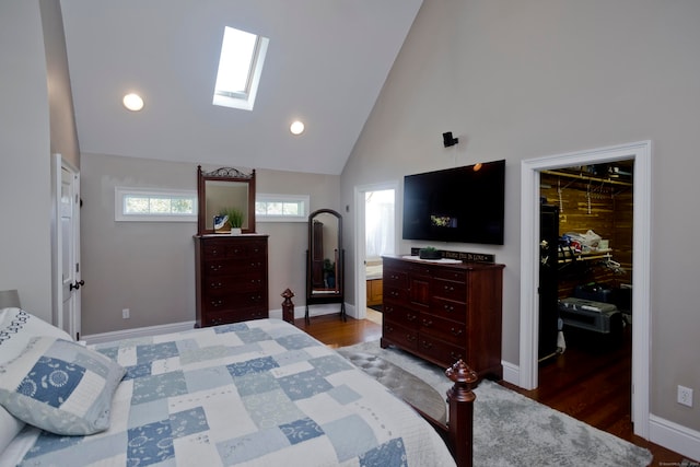 bedroom with high vaulted ceiling, connected bathroom, a skylight, and dark hardwood / wood-style floors