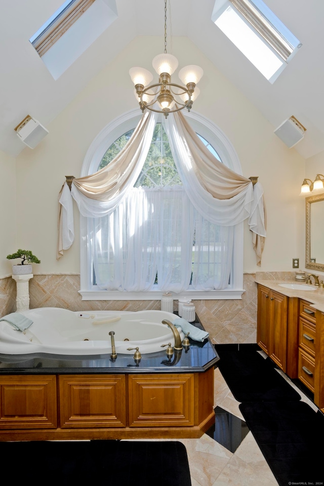 bathroom with vanity, a bathing tub, a chandelier, lofted ceiling with skylight, and tile walls