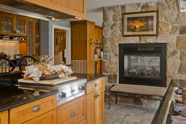 kitchen featuring backsplash and a stone fireplace