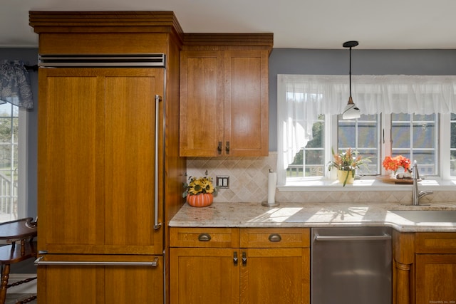 kitchen featuring light stone counters, pendant lighting, sink, and decorative backsplash