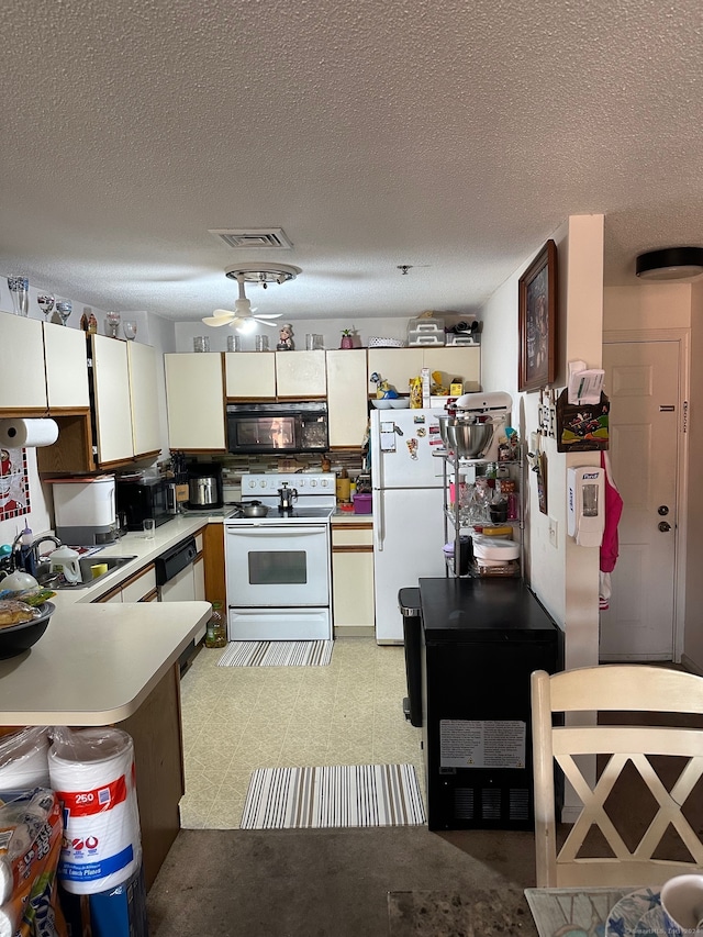 kitchen featuring kitchen peninsula, white appliances, a textured ceiling, and sink