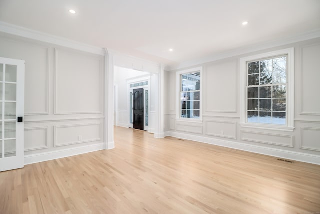 empty room featuring light wood-type flooring and ornamental molding