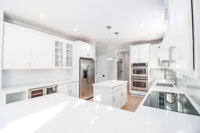 kitchen with white cabinetry, sink, decorative light fixtures, a kitchen island, and appliances with stainless steel finishes