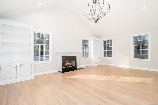 unfurnished living room with high vaulted ceiling, a chandelier, and light wood-type flooring