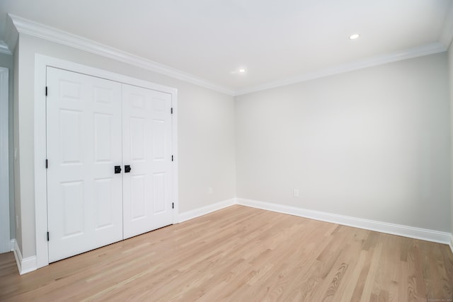 unfurnished bedroom featuring light wood-type flooring, ornamental molding, and a closet