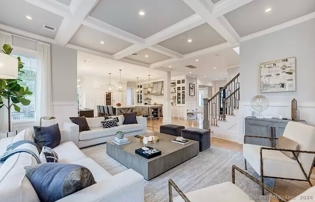 living room featuring ornamental molding, coffered ceiling, light wood-type flooring, and beam ceiling