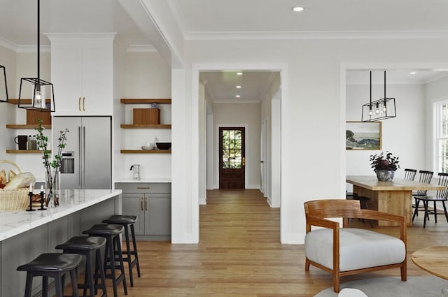 kitchen featuring light stone countertops, gray cabinetry, light hardwood / wood-style flooring, decorative light fixtures, and high quality fridge