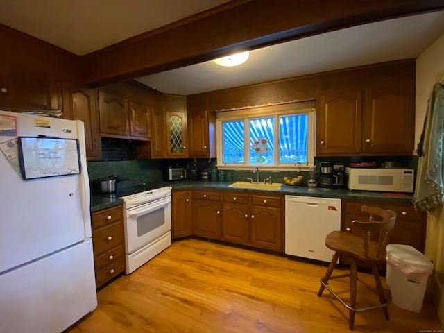 kitchen featuring backsplash, light wood-type flooring, white appliances, and sink