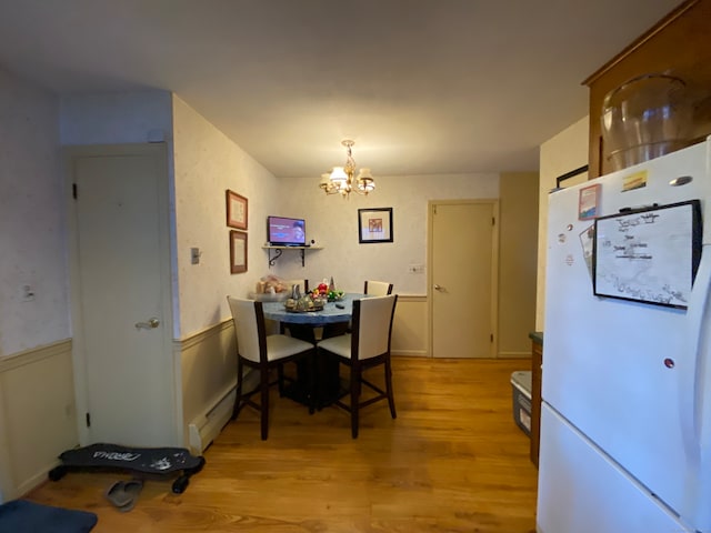 dining room with an inviting chandelier, baseboard heating, and light hardwood / wood-style flooring