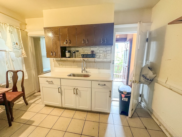 kitchen featuring decorative backsplash, white cabinets, light tile patterned floors, and sink