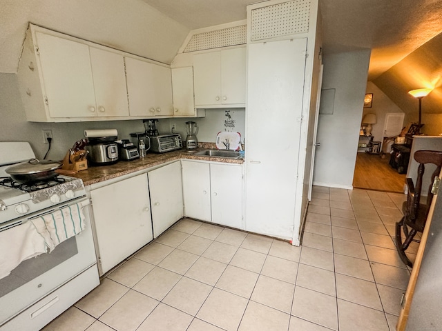 kitchen featuring white cabinets, lofted ceiling, sink, and gas range gas stove