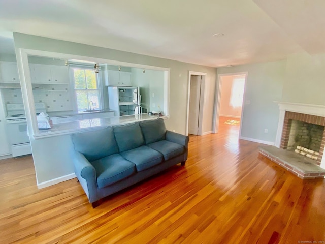 living room featuring light wood-type flooring, a fireplace, and sink