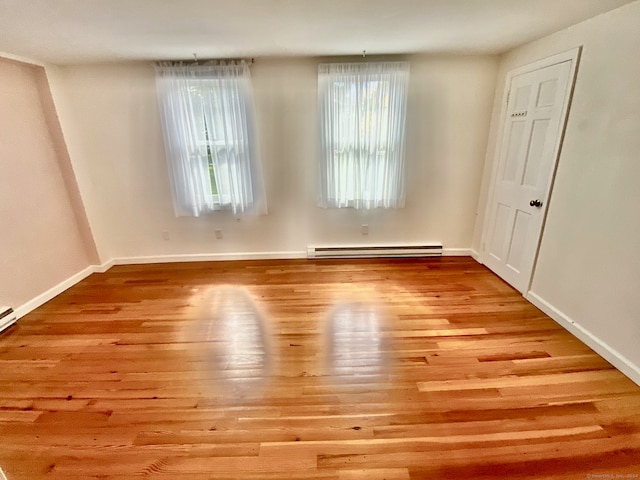 empty room with light wood-type flooring and a baseboard heating unit