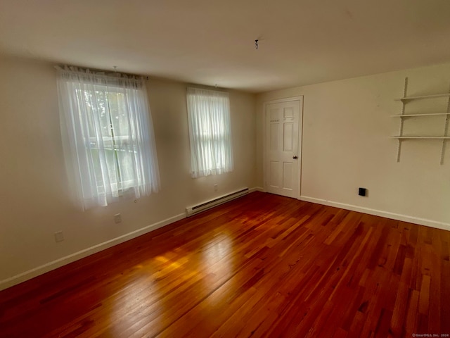 unfurnished room featuring wood-type flooring and a baseboard radiator