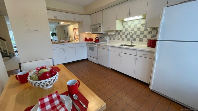 kitchen featuring dark tile patterned floors, sink, white cabinetry, decorative backsplash, and white appliances