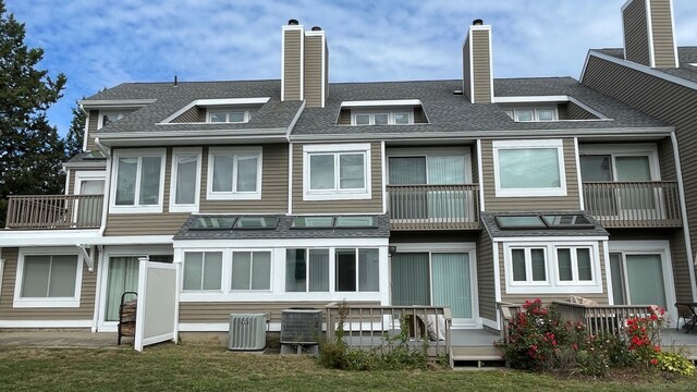 back of house with a balcony, cooling unit, and a yard