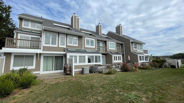 back of property featuring a balcony, central AC unit, and a yard