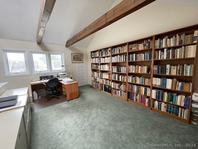 carpeted office with vaulted ceiling with beams