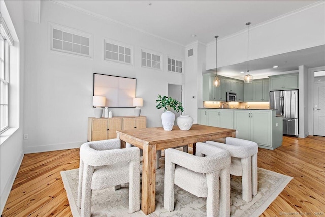 dining room featuring crown molding, plenty of natural light, and light hardwood / wood-style floors