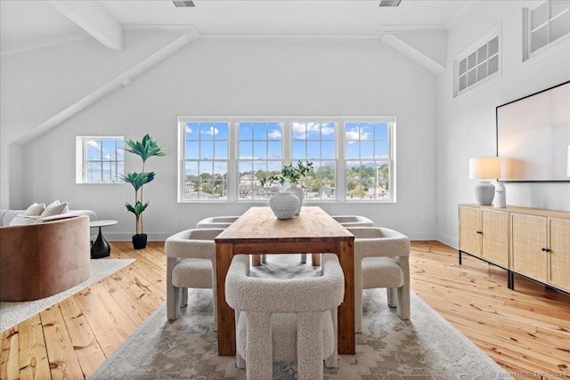 dining space featuring hardwood / wood-style floors, crown molding, a wealth of natural light, and beamed ceiling