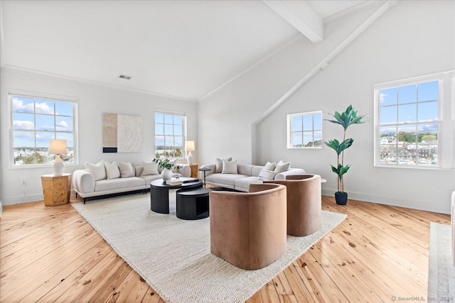 living room with light hardwood / wood-style flooring, beamed ceiling, and plenty of natural light