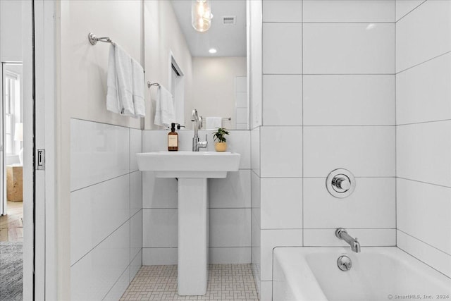 bathroom featuring tiled shower / bath combo and tile walls