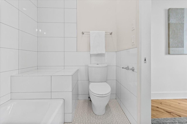 bathroom with tile patterned flooring, tile walls, and toilet