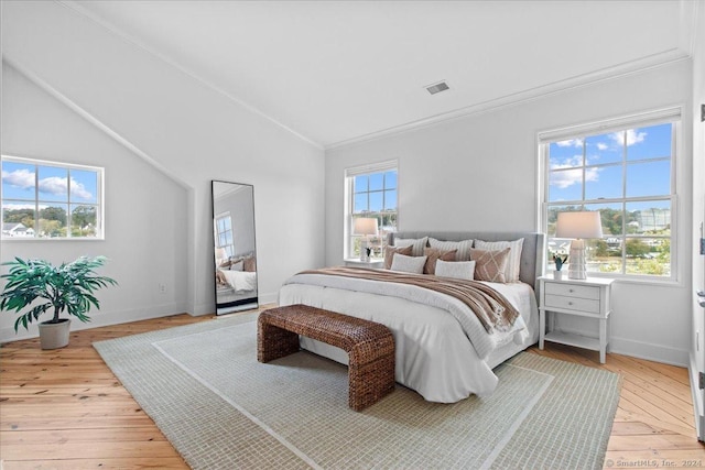 bedroom with light wood-type flooring, ornamental molding, and vaulted ceiling