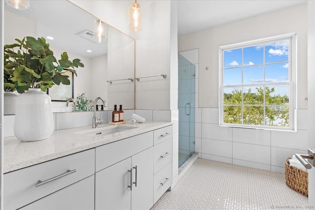 bathroom with tile patterned floors, vanity, an enclosed shower, and tile walls