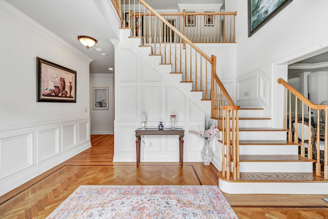 staircase with crown molding, a high ceiling, and parquet floors